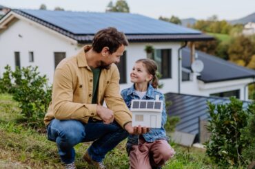 Little,Girl,With,Her,Dad,Holding,Paper,Model,Of,House